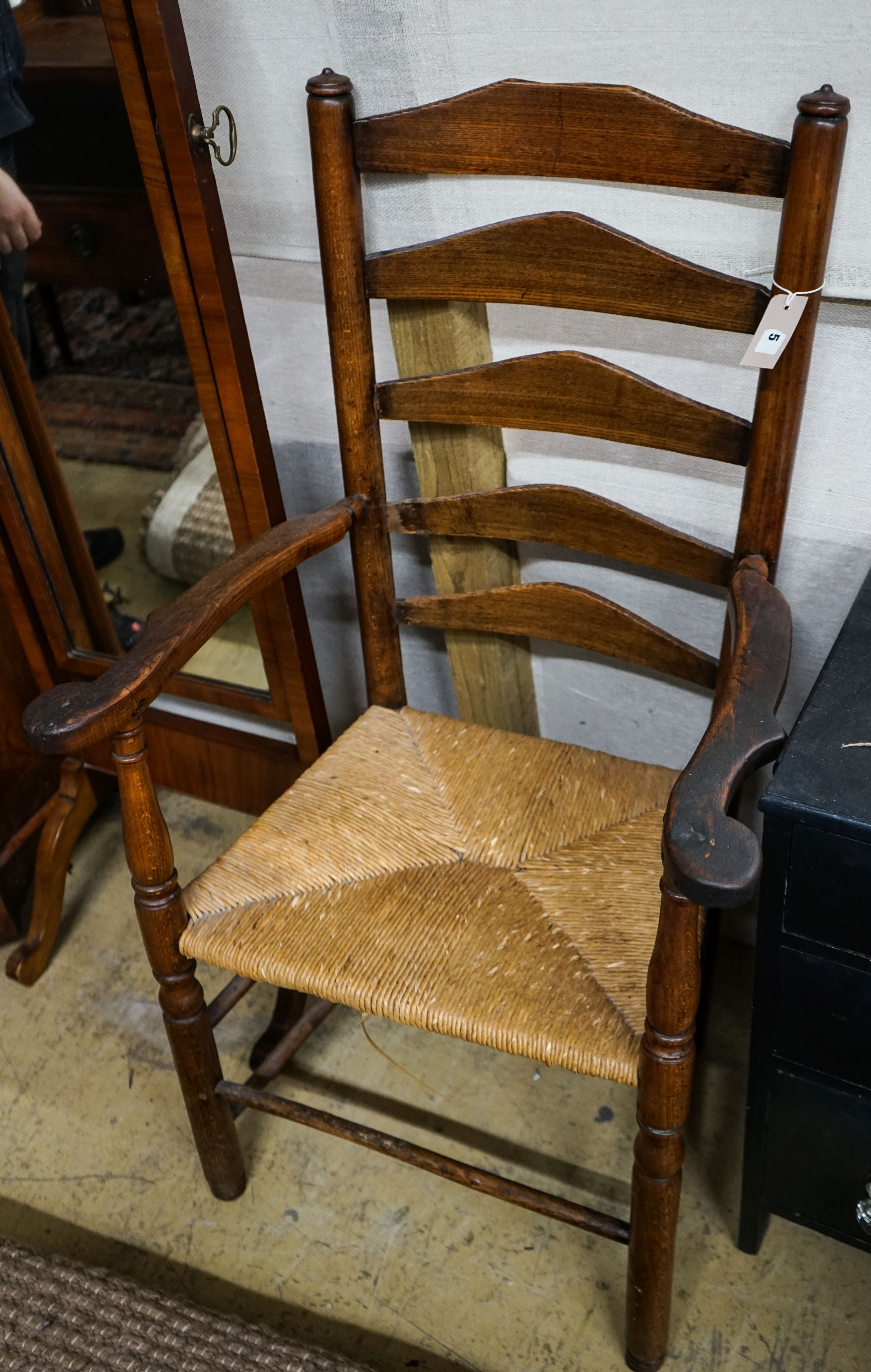 An early 19th century ash and elm rush seated ladder back elbow chair, width 63cm, depth 44cm, height 107cm